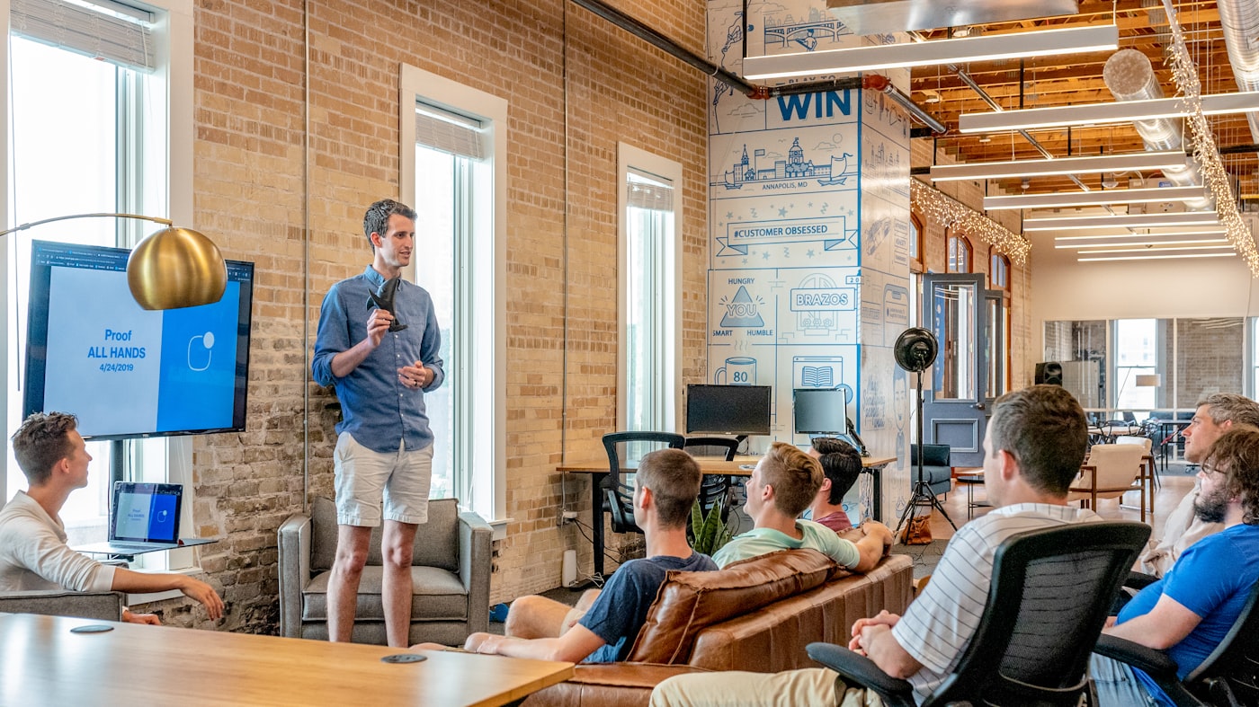 Team gathered in a brick-walled office for an all-hands presentation