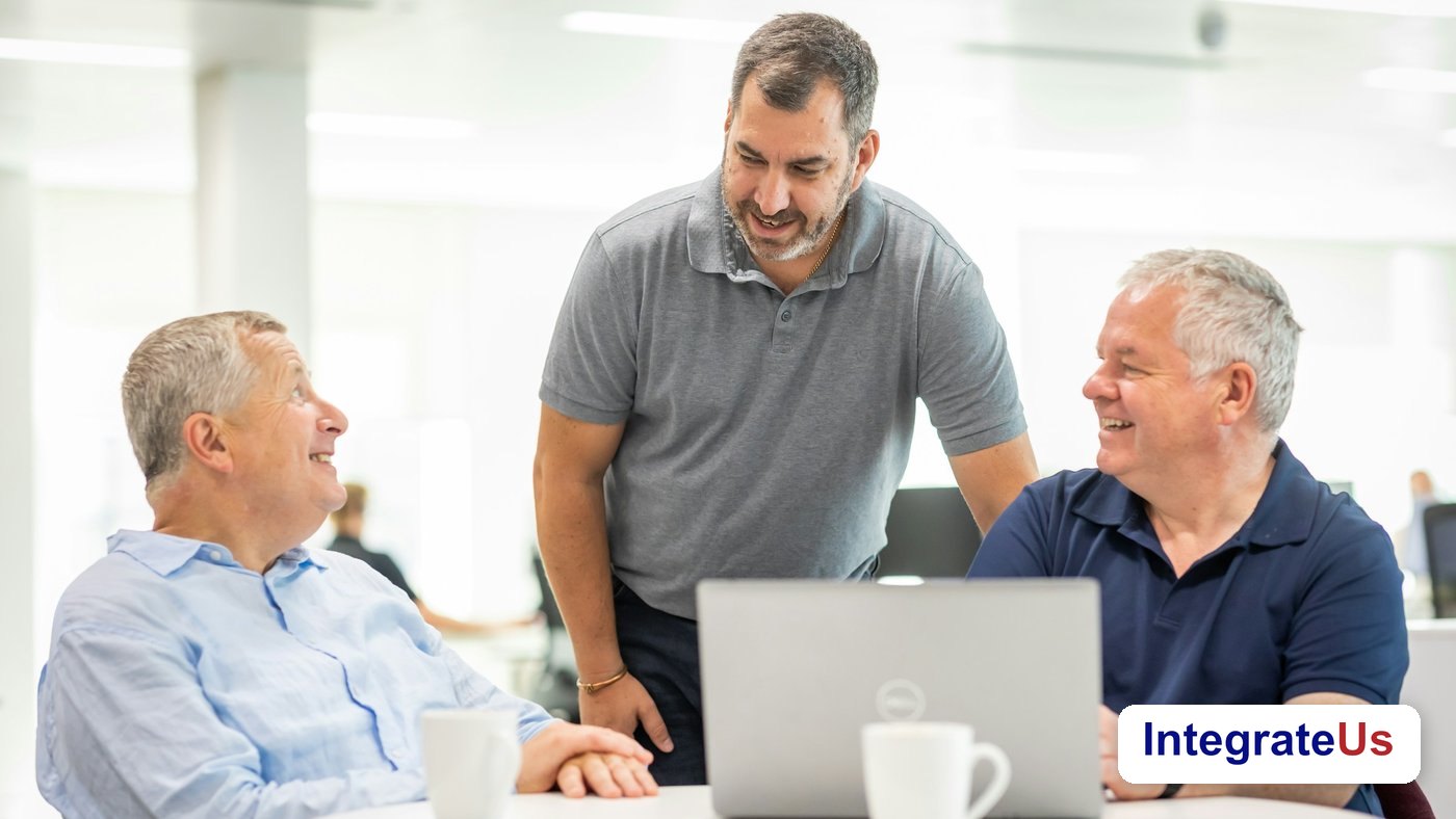 Three colleagues discuss a project around a laptop at an office table